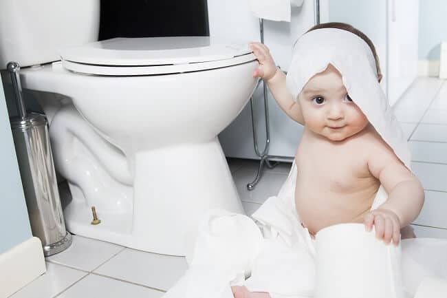 Toddler playing with toilet paper in bathroom