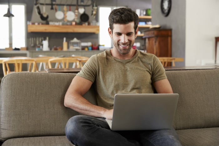 man-sitting-on-couch-looking-on-computer