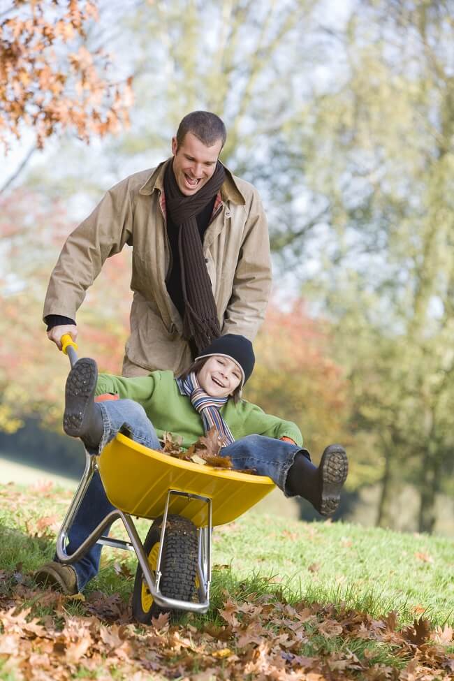 dad and son playing in fall leaves