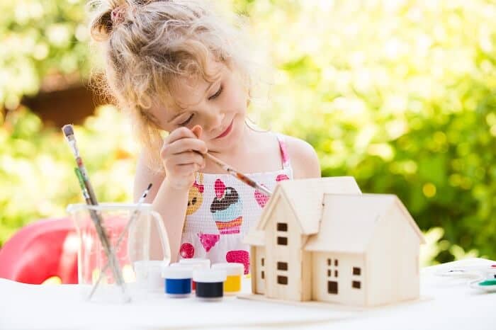 girl painting wooden house model