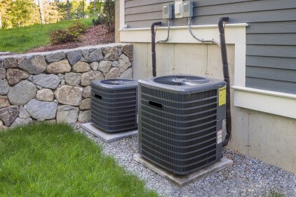 Two residential air conditioner units outside of a home.